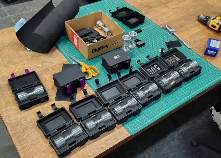 Early Infinity Chalice builds in open black cases on the workshop bench, surrounded by tools and parts