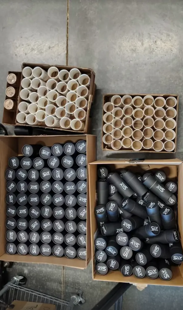 Boxes of kraft tubes and black tubes printed with the Sly Designs logo