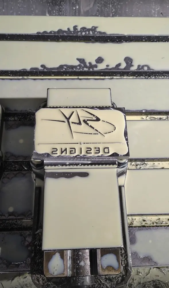 Sly Designs logo foil-stamp die machined in reverse, held in a CNC vise