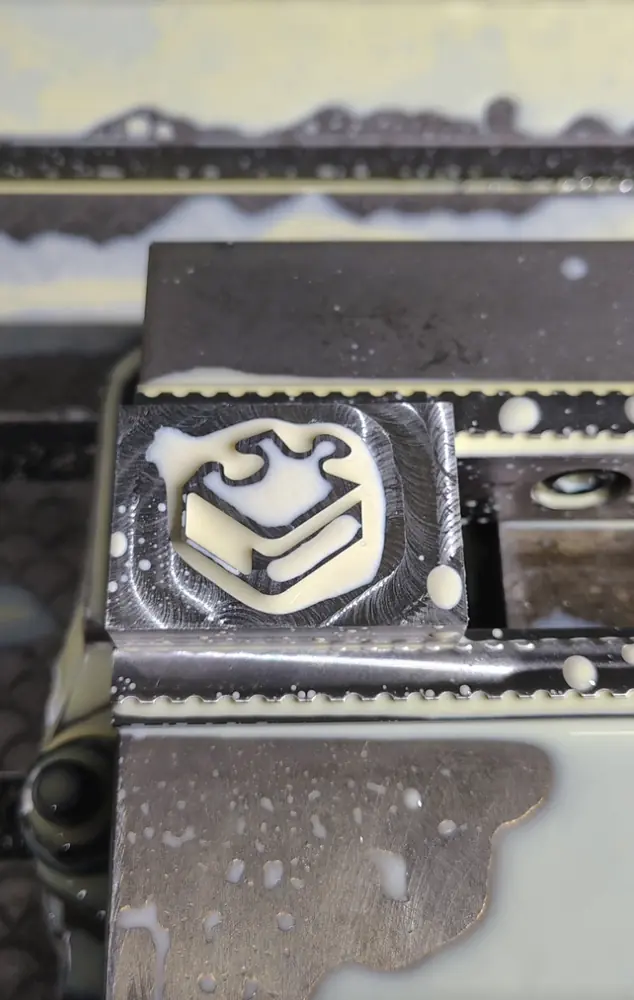 Foil-stamp die with the NEUTRINO logo machined into steel, covered in coolant